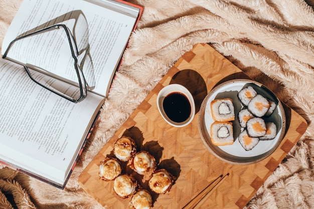 Foto japanse sushibroodjes die op lichte raad, beige achtergrond worden gediend. sushirolletjes philadelphia, warm gebakken broodje met room, maki, eetstokjes en sojasaus