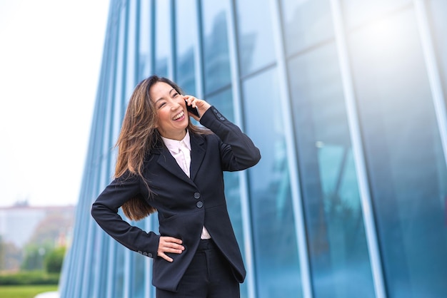 Japanse volwassen vrouw aan de telefoon zakenpersoon verheugt zich over de behaalde successen concept van gelijkheid en gendergelijkheid in de wereld van werk en financiën koude filter en zonlicht effect