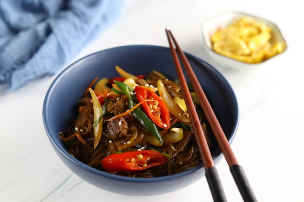 Japchae Korean Glass noodle roerbak Geserveerd in de kom met witte achtergrond