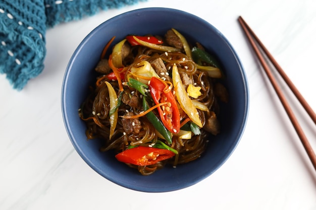 Обжаренная корейская стеклянная лапша Japchae Подается в миске на белом фоне