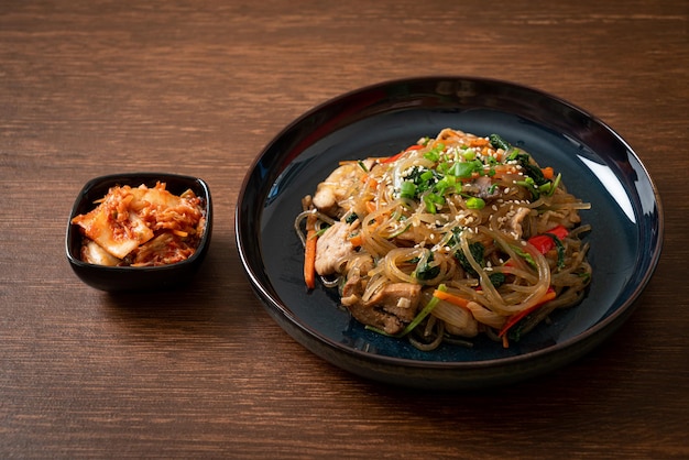 japchae of roergebakken Koreaanse vermicelli-noedels met groenten en varkensvlees gegarneerd met witte sesam - Koreaanse traditionele voedselstijl