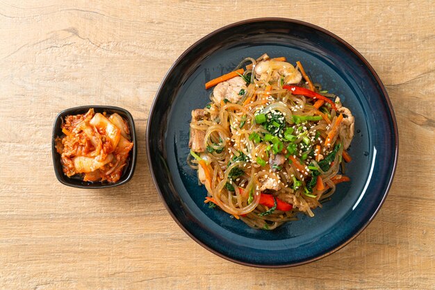 japchae of roergebakken Koreaanse vermicelli-noedels met groenten en varkensvlees gegarneerd met witte sesam - Koreaanse traditionele voedselstijl