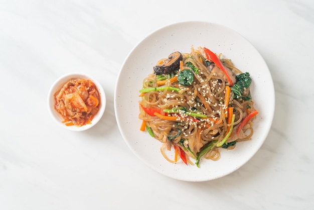 japchae or stir-fried Korean vermicelli noodles with vegetables and pork topped with white sesame - Korean traditional food style