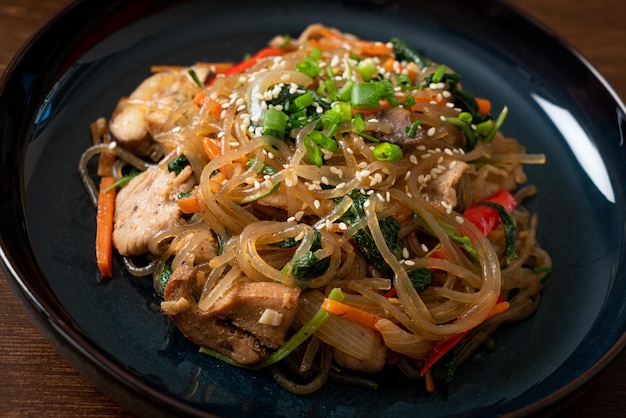 Japchae or stirfried Korean vermicelli noodles with vegetables and pork topped with white sesame