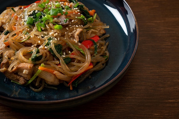 Japchae or stirfried Korean vermicelli noodles with vegetables and pork topped with white sesame