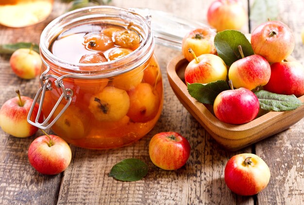 Jar of apple jam with fresh fruits on wooden table