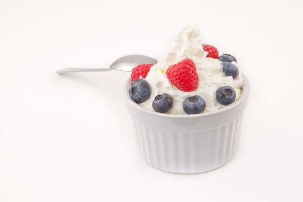 Jar of berries and whipped cream with spoon