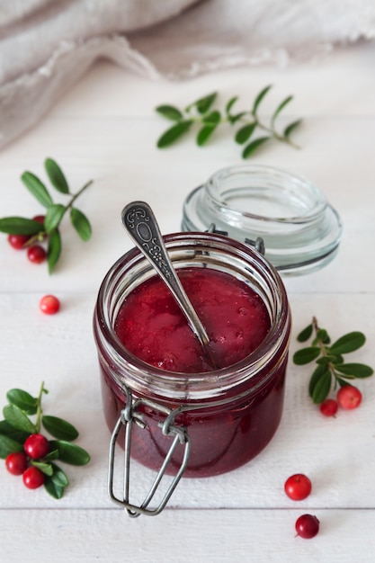 Vasetto di marmellata di bacche con un cucchiaio e frutti di bosco