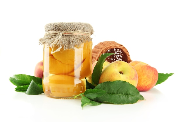 Jar of canned peaches and fresh peaches isolated on white