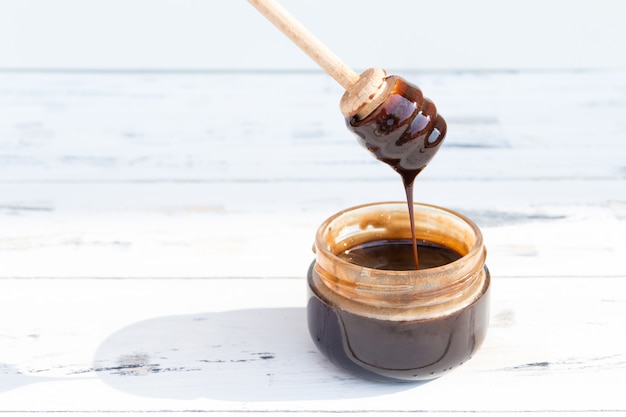 A jar of chocolate dessert, honey or cosmetic masque on white wooden table