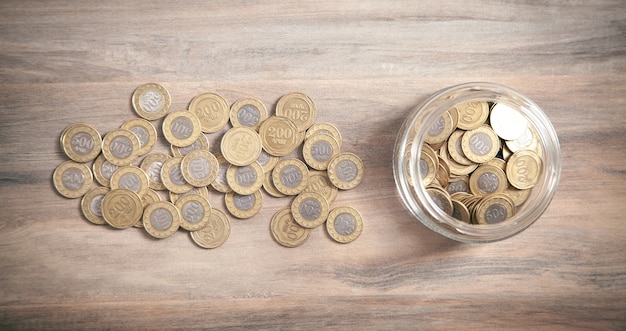 Jar of coins on wooden background.