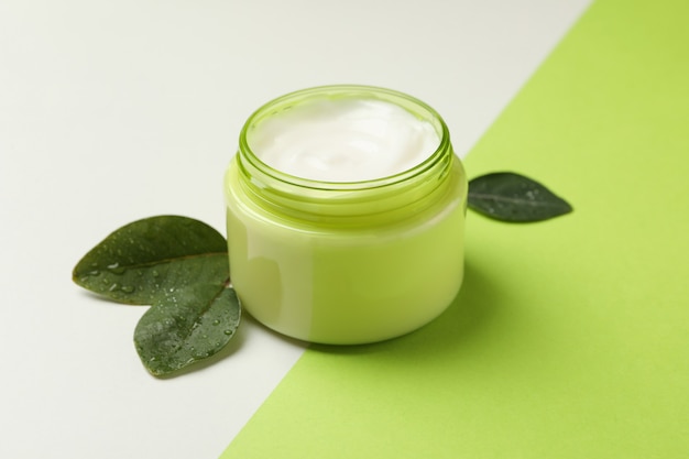 Jar of cosmetic cream and leaves