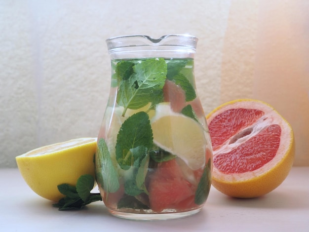 A jar of detox water or flavored water with white and red grapefruit wedges and fresh mint leaves