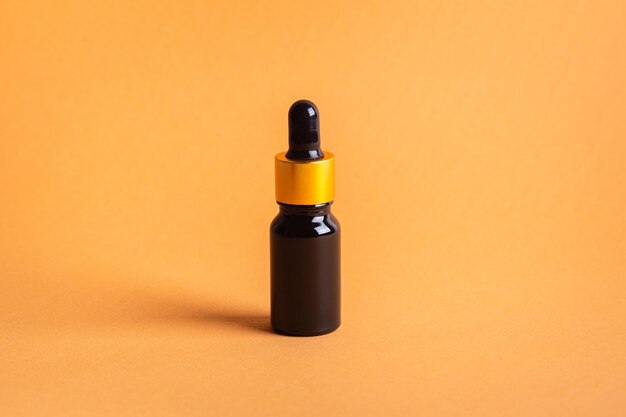 Jar of facial cosmetic oil on orange background