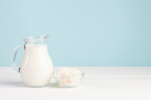 Foto vaso pieno di latte e formaggio in una ciotola