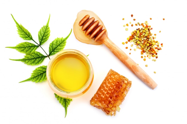 Jar of fresh honey, honeycomb and pollen on a white background.