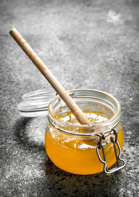 Jar of fresh honey on rustic table.