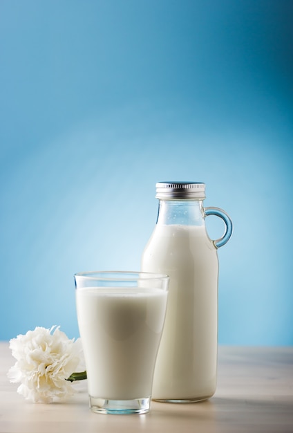 Jar and glass of milk on a wooden table and blue background