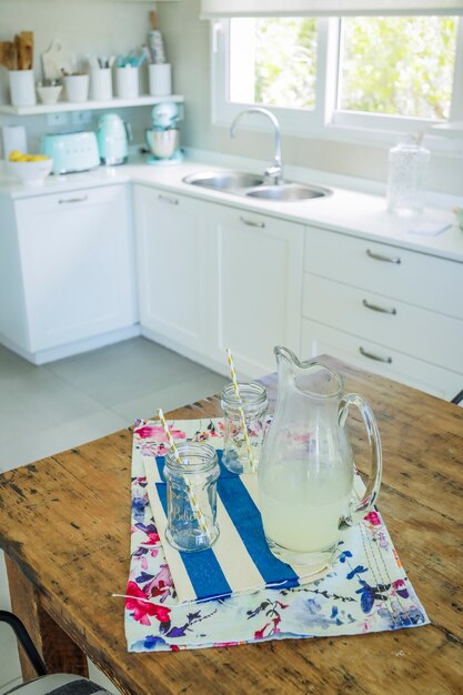 Jar and glasses with lemonade juice in the kitchen