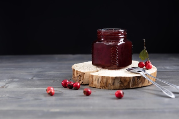 Jar of healthy jam from hawthorn fruits on a wooden board