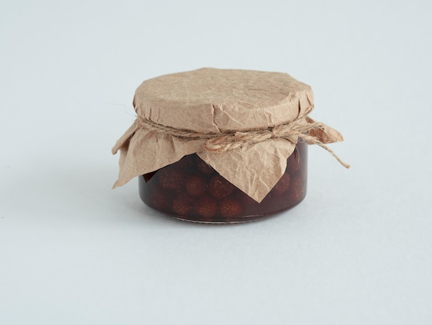 A jar of homemade strawberry jam covered with parchment tied with a jute rope