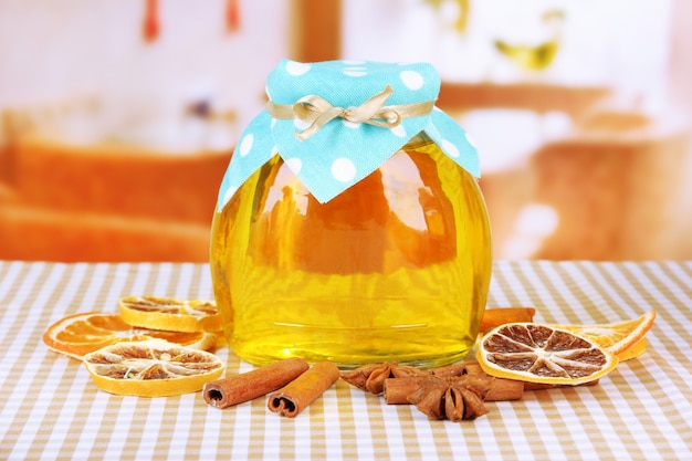 Jar of honey and dried lemon slices on bright surface