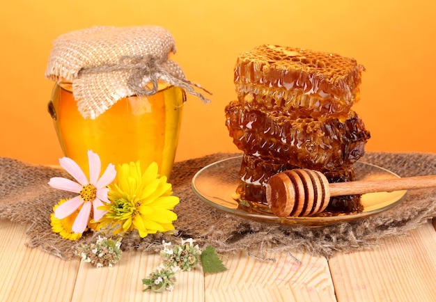 오렌지 배경의 나무 테이블에 꿀과 벌집 항아리