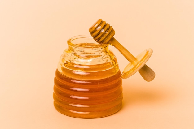 Jar of honey isolated on beige background