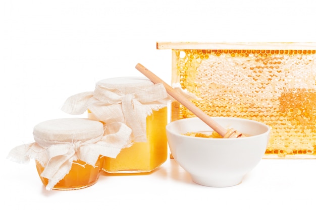 Vaso di miele e bastone isolato su sfondo bianco