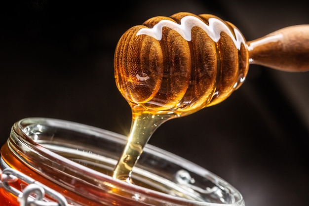 Photo jar of honey with dipper closeup - studio shot.
