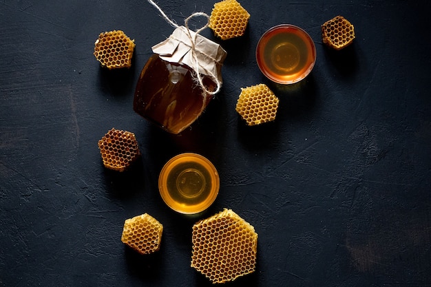 Jar of honey with honeycomb on black table