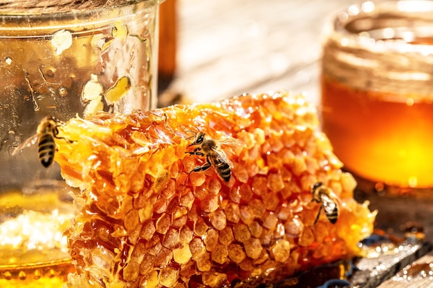 Jar of honey with honeycomb with wooden dipper on wooden table