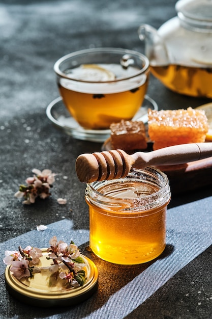 Jar of honey with honeycombs and a stick