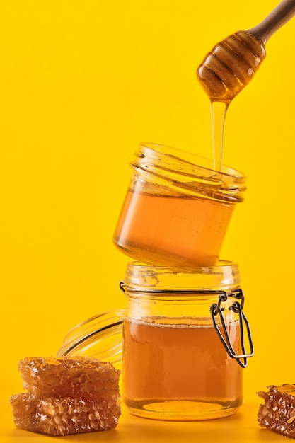 Jar of honey with honeycombs and a stick