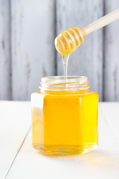 Jar of honey on wooden table.