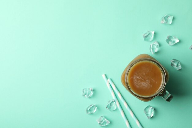 Foto barattolo di caffè ghiacciato, cubetti di ghiaccio e cannucce su sfondo di menta