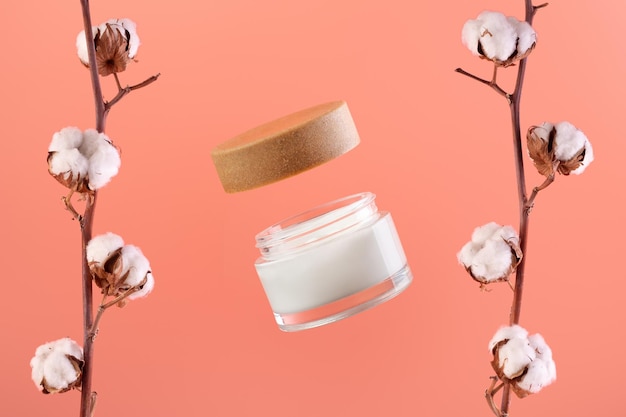 A jar of moisturizer and cotton on the sides natural beauty\
product levitating organic cosmetics