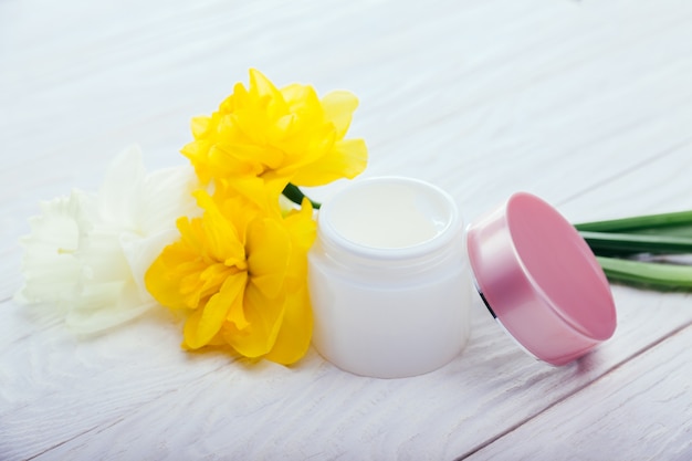 Jar of natural facial cream with flowers. Organic cosmetics