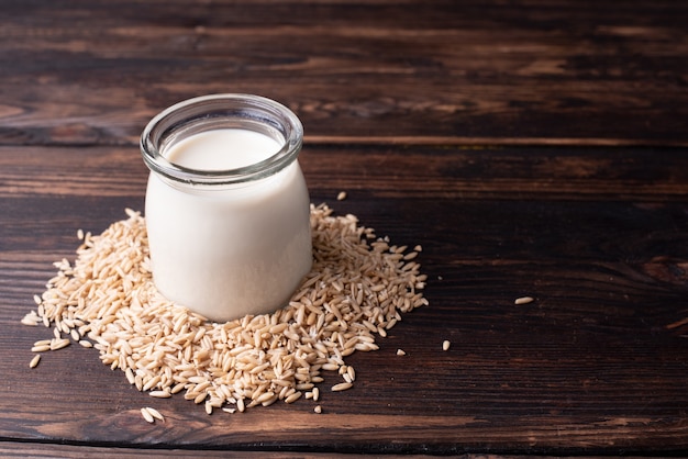 Jar of oat milk in oatmeal on wooden table