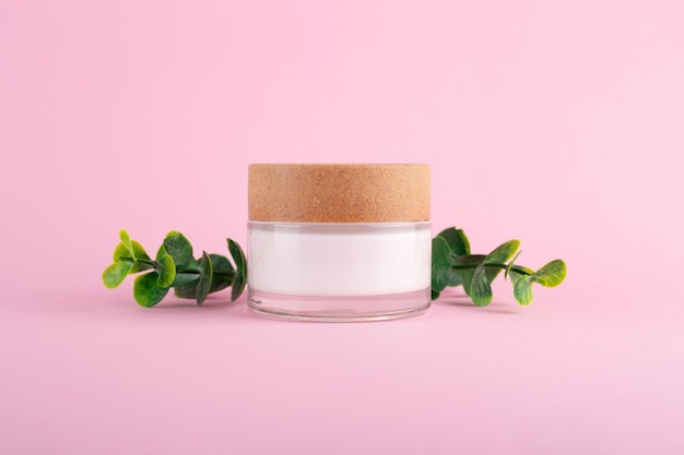 Jar of organic cream with eucalyptus leaves on pink background Flat lay top view copy space Natural