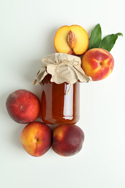 jar of peach jam and ingredients on white background