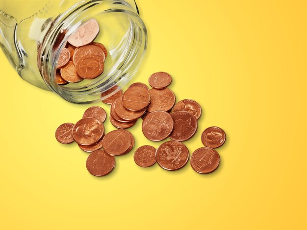 Jar of pennies spilling out on refective white