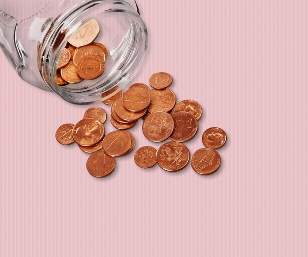 Photo jar of pennies spilling out on refective white