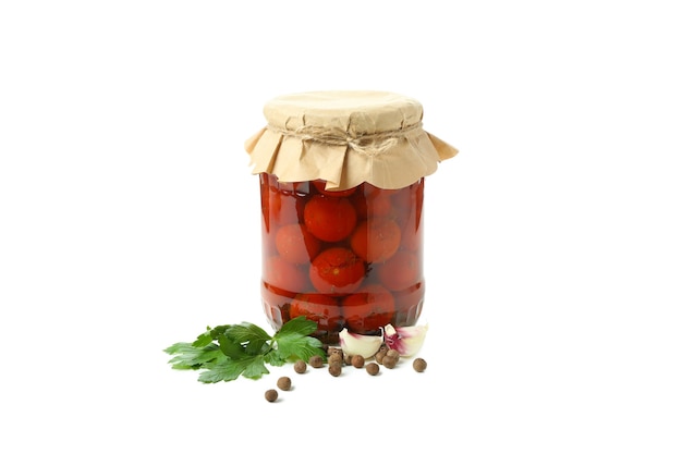 Jar of pickled tomatoes and ingredients isolated on white background