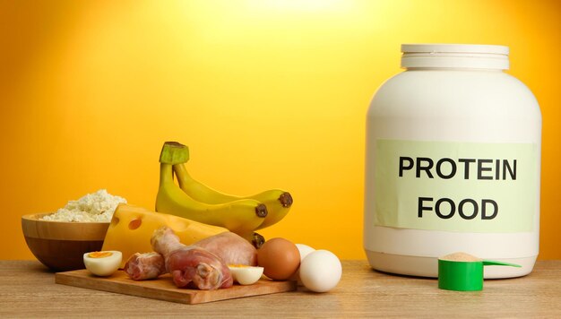 Jar of protein powder and food with protein on yellow background