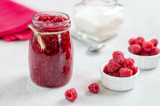 Vaso di marmellata di lamponi e frutti di bosco freschi su un tavolo bianco messa a fuoco selettiva