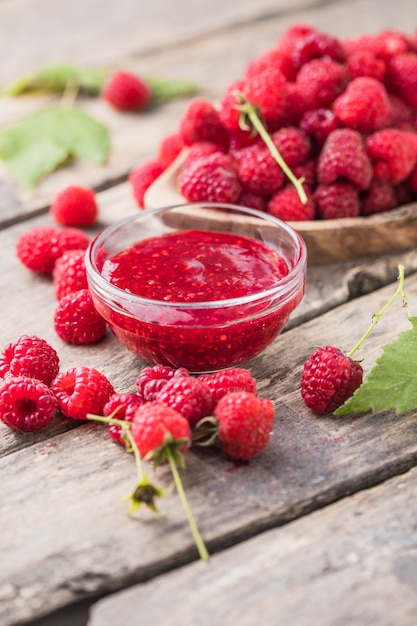 Jar of raspberry jam and fresh berries with leaves. Sweet dessert