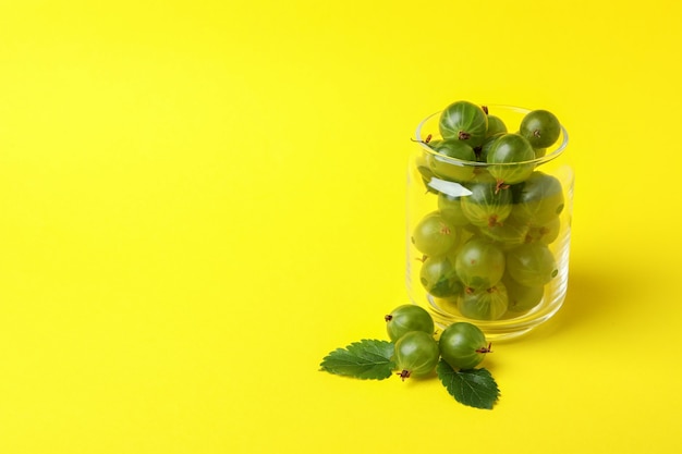 Jar of ripe gooseberry on yellow background