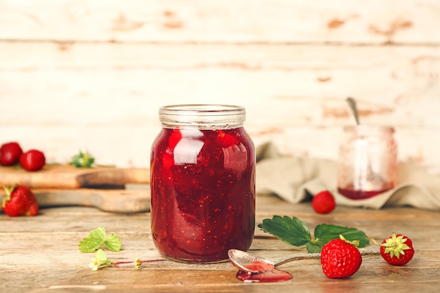 Jar of tasty strawberry jam on table