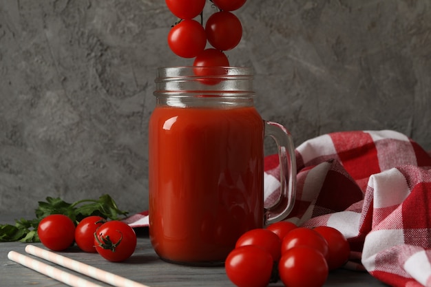 Jar of tomato juice, tomatoes and kitchen towel on wooden